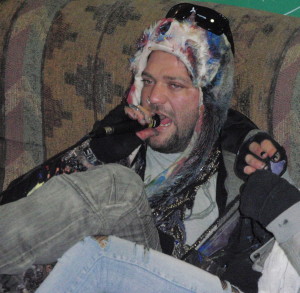 Bam Margera sits on a couch and belts out vocals during a jam session at his art show Tuesday night.