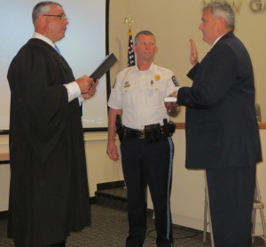 Magisterial District Judge Matthew Seavey (left) swears in Magorry as New Garden Police Chief Gerald Simpson holds the Bible.