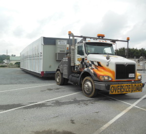 The first of three sections of a temporary police station is hauled onto the site that contains a mold-infested  facility.