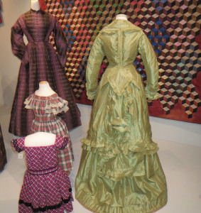 Two women’s dresses, a green striped silk and a purple and black plaid silk taffeta, and two child’s dresses, a red, black and white plaid cotton and a magenta, black and white plaid wool trimmed in black velvet, were worn in Chester County in the 1860s and 1870s.